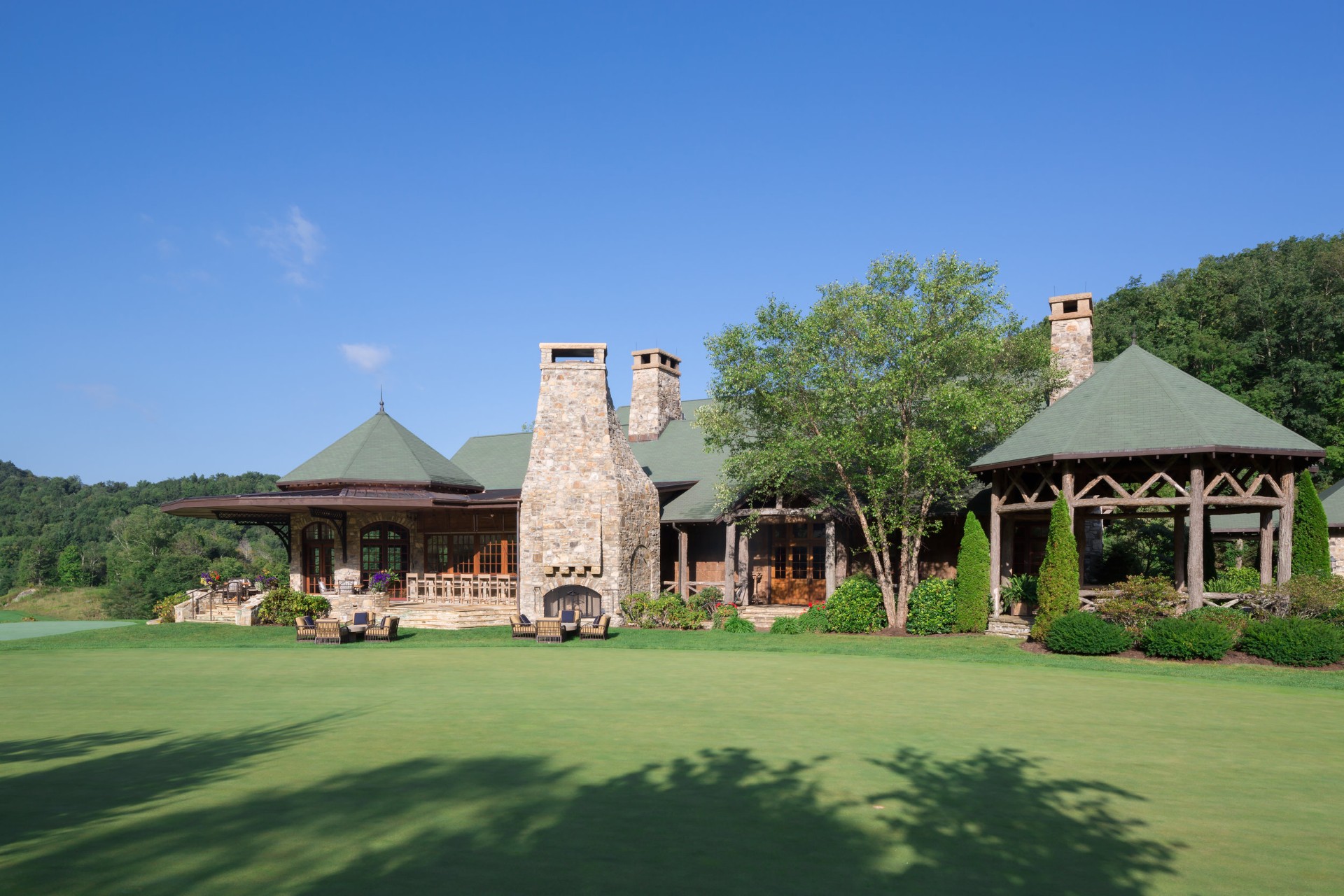 Diamond Creek clubhouse lanai side exterior with stone chimneys and timber pavilions